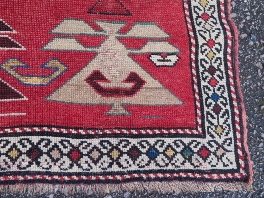 An antique South Caucasian Karabagh hand-knotted wool rug with repeating geometric motifs across a deep red field and a patterned border. View IX