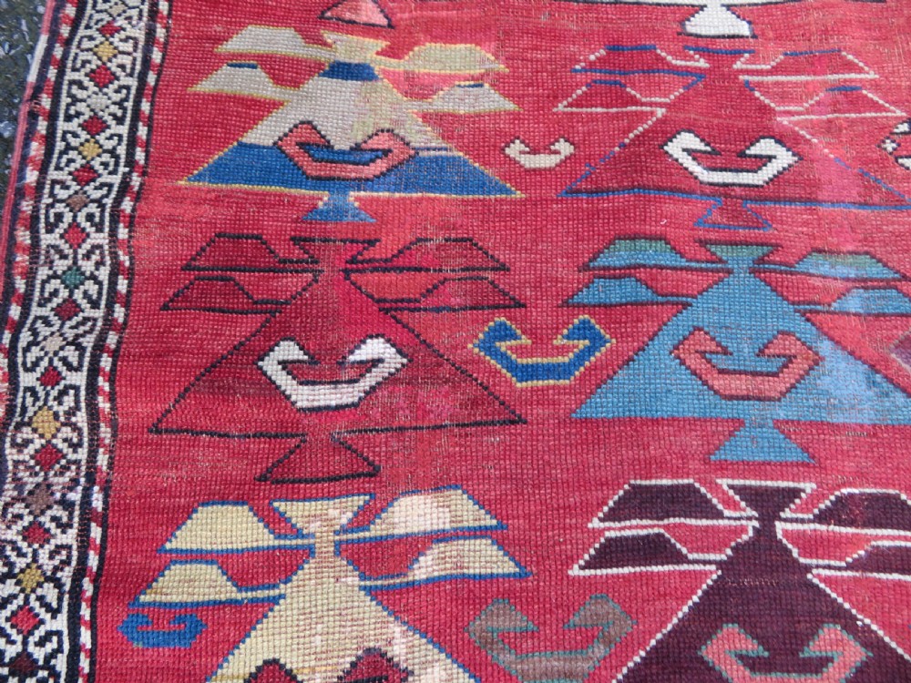 An antique South Caucasian Karabagh hand-knotted wool rug with repeating geometric motifs across a deep red field and a patterned border. View XV