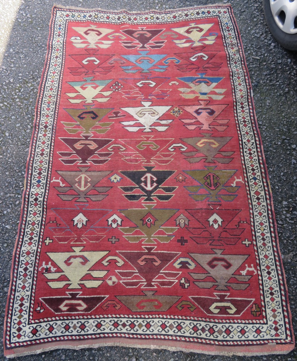 An antique South Caucasian Karabagh hand-knotted wool rug with repeating geometric motifs across a deep red field and a patterned border. View II