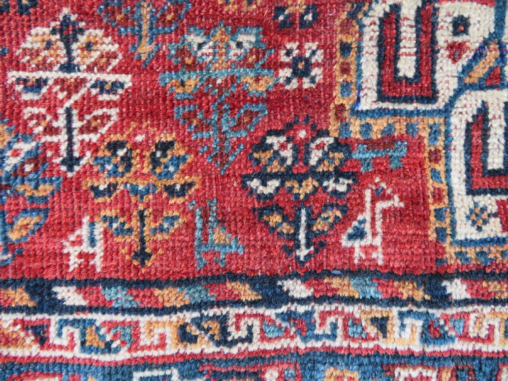 An antique South West Persian Khamseh tribal wool rug featuring a blue central diamond field filled with geometric bird motifs surrounded by a red border. View VIII