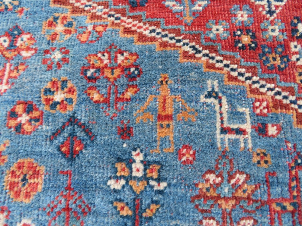 An antique South West Persian Khamseh tribal wool rug featuring a blue central diamond field filled with geometric bird motifs surrounded by a red border. View XI