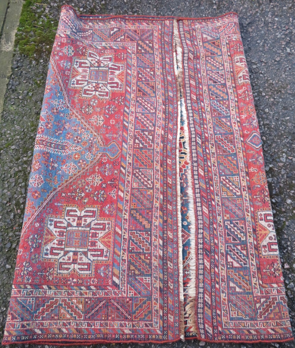 An antique South West Persian Khamseh tribal wool rug featuring a blue central diamond field filled with geometric bird motifs surrounded by a red border. View XV