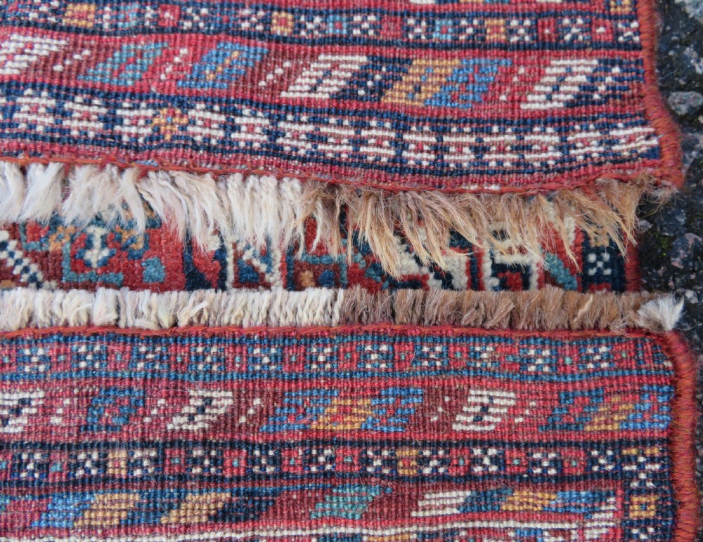 An antique South West Persian Khamseh tribal wool rug featuring a blue central diamond field filled with geometric bird motifs surrounded by a red border. View XVI