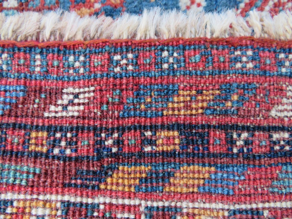 An antique South West Persian Khamseh tribal wool rug featuring a blue central diamond field filled with geometric bird motifs surrounded by a red border. View XVII