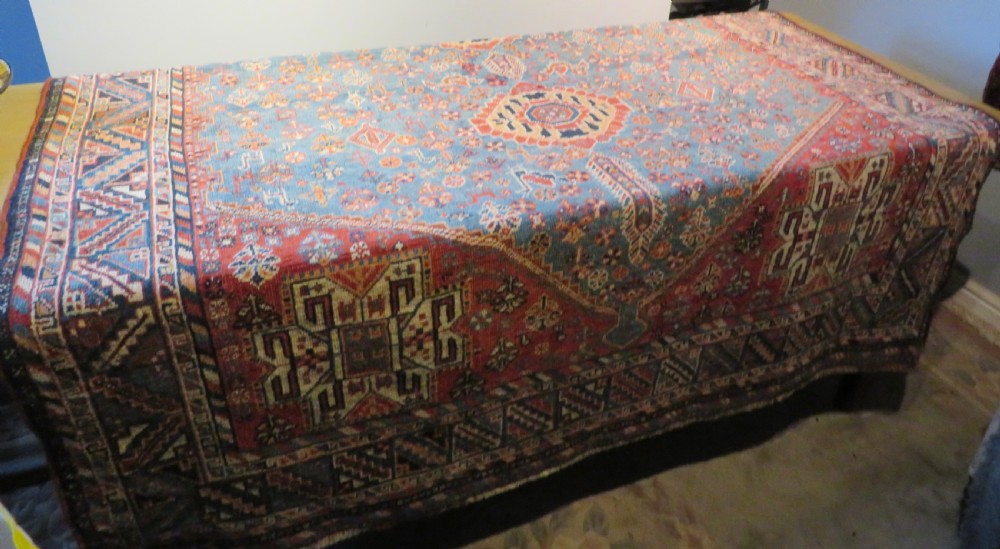 An antique South West Persian Khamseh tribal wool rug featuring a blue central diamond field filled with geometric bird motifs surrounded by a red border. View XXII