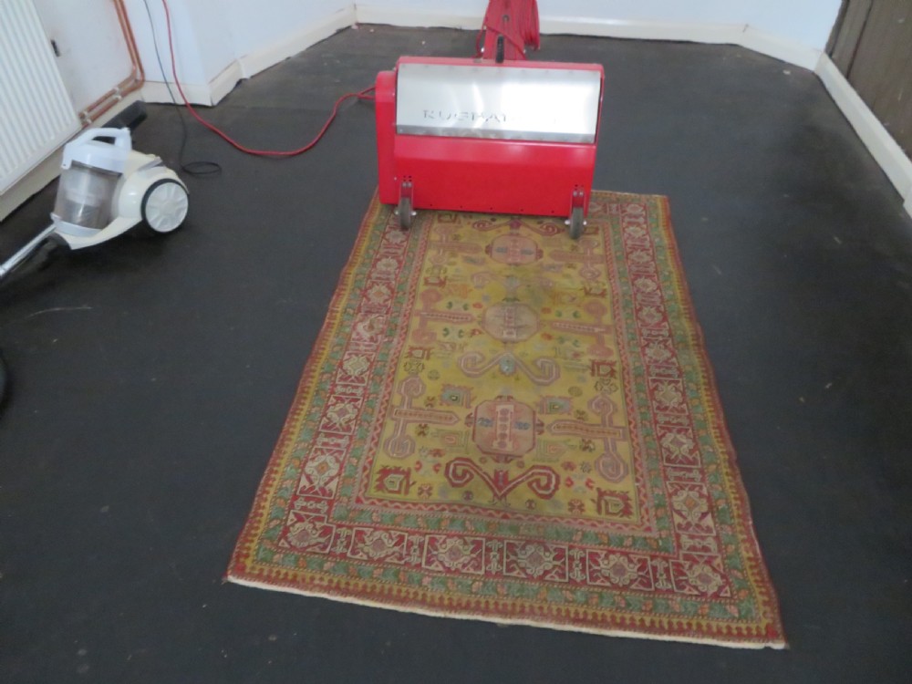 An antique hand-knotted Caucasian rug featuring a distressed yellow central field patterned with geometric ram horn motifs framed by red and green decorative borders. View XIX