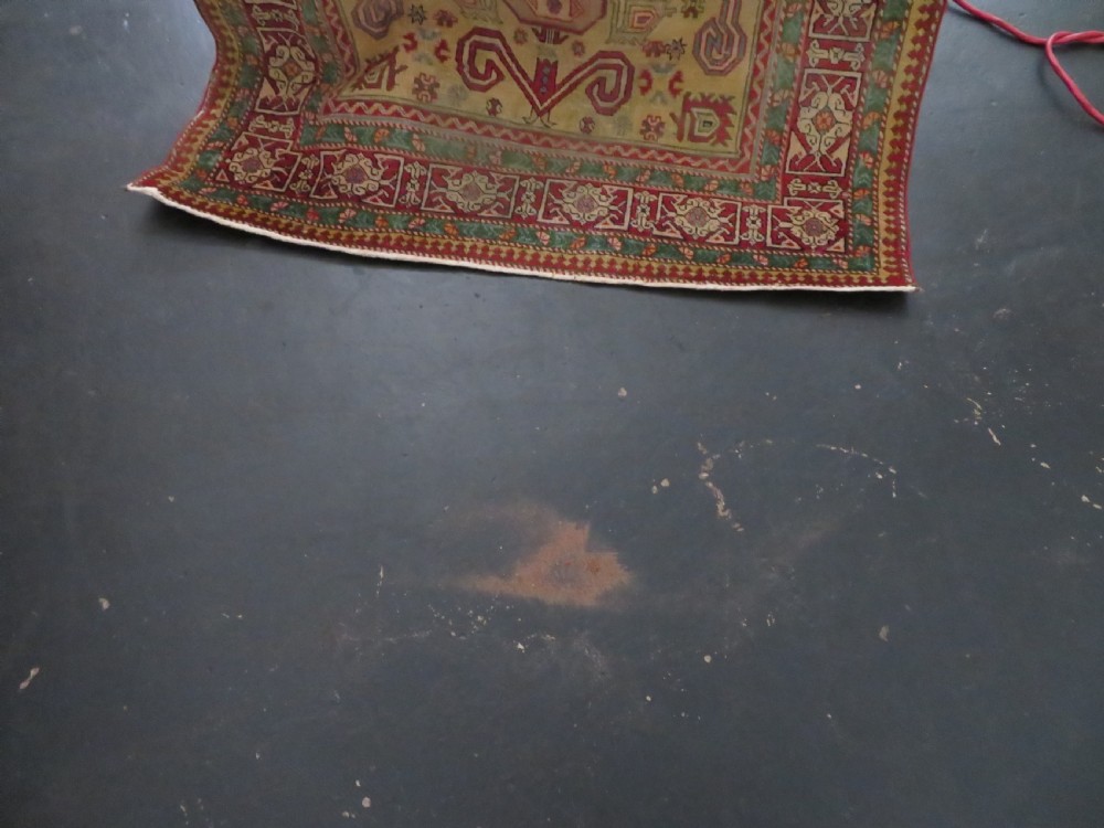 An antique hand-knotted Caucasian rug featuring a distressed yellow central field patterned with geometric ram horn motifs framed by red and green decorative borders. View XX