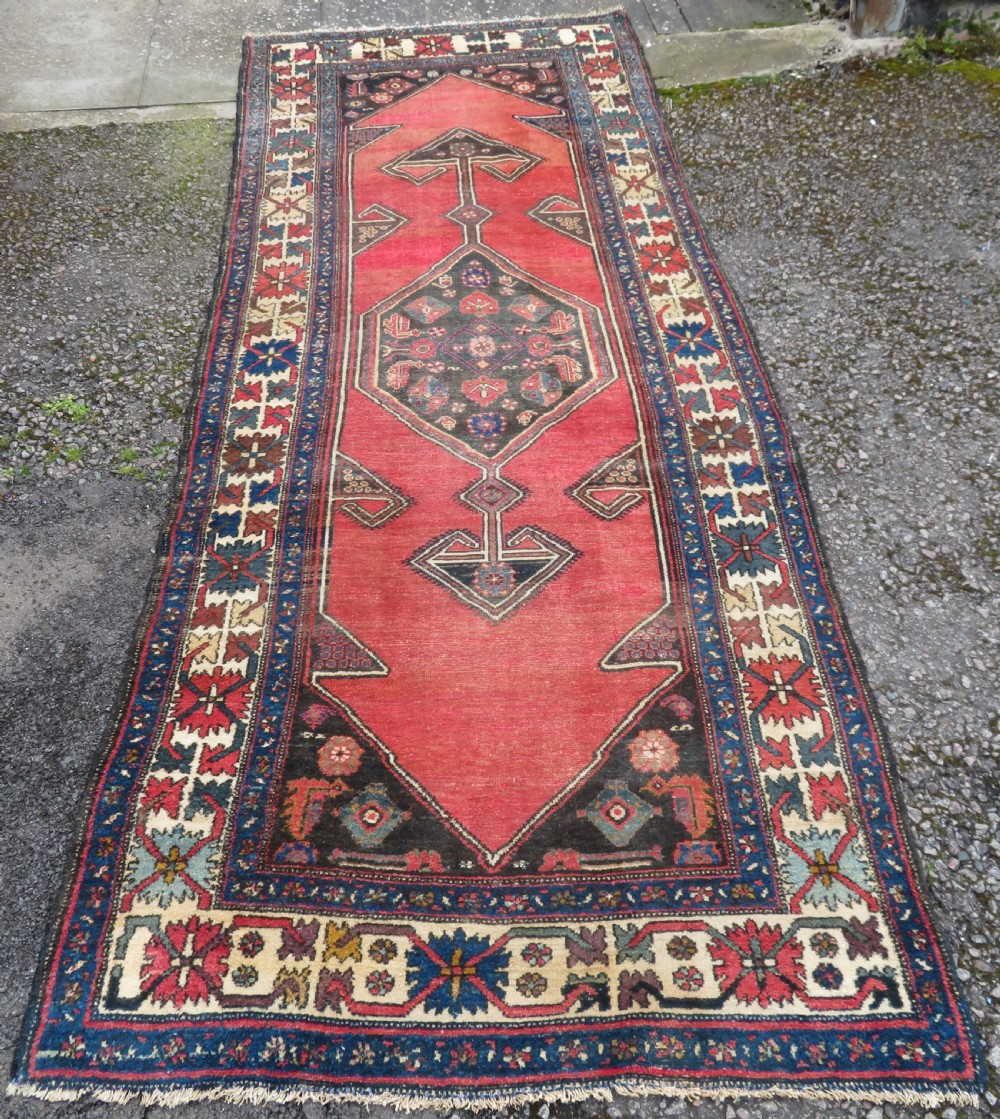 An antique Northwest Persian Zanjan Kelleh rug featuring a red field with diamond medallions surrounded by a wide cream, blue, and red Harshang crab border.