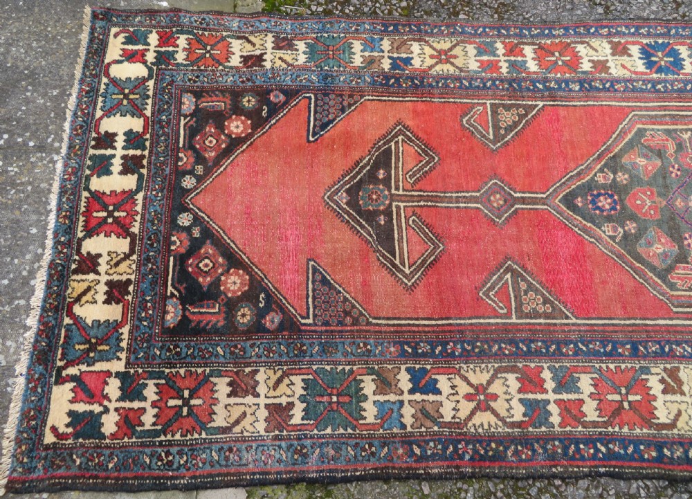 An antique Northwest Persian Zanjan Kelleh rug featuring a red field with diamond medallions surrounded by a wide cream, blue, and red Harshang crab border. View III
