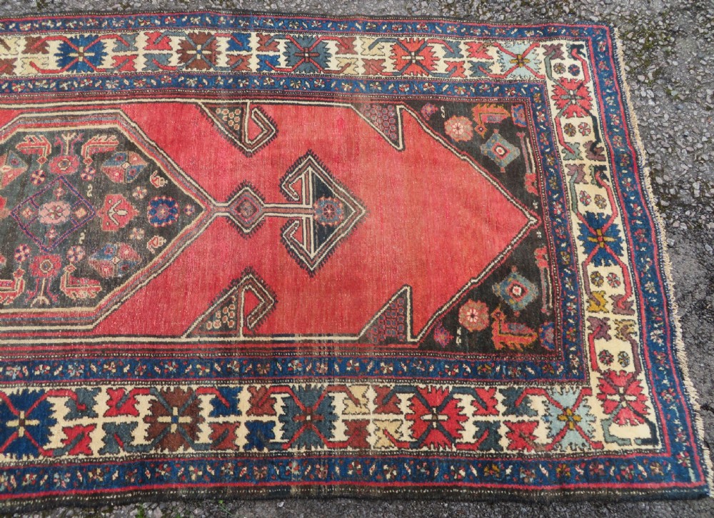 An antique Northwest Persian Zanjan Kelleh rug featuring a red field with diamond medallions surrounded by a wide cream, blue, and red Harshang crab border. View IV