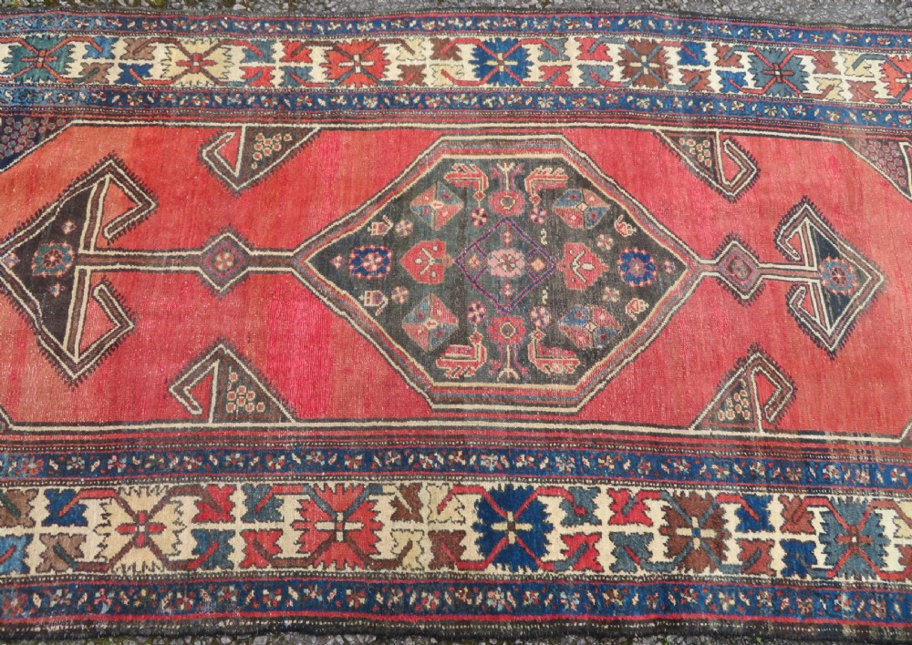 An antique Northwest Persian Zanjan Kelleh rug featuring a red field with diamond medallions surrounded by a wide cream, blue, and red Harshang crab border. View V