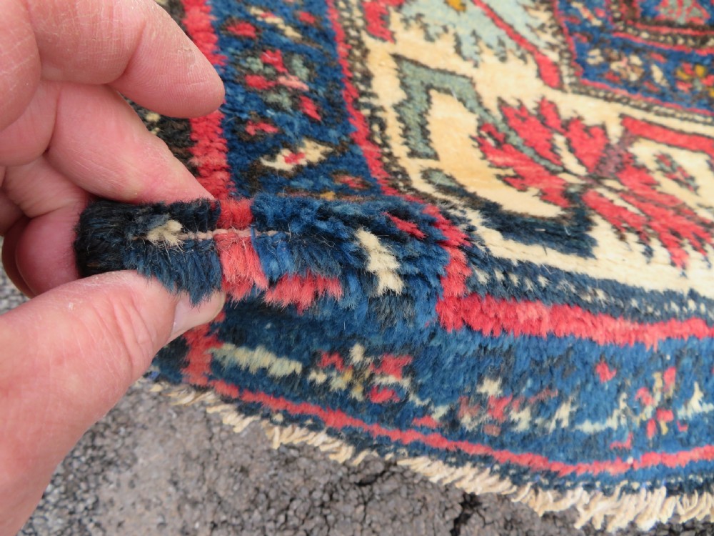 An antique Northwest Persian Zanjan Kelleh rug featuring a red field with diamond medallions surrounded by a wide cream, blue, and red Harshang crab border. View X