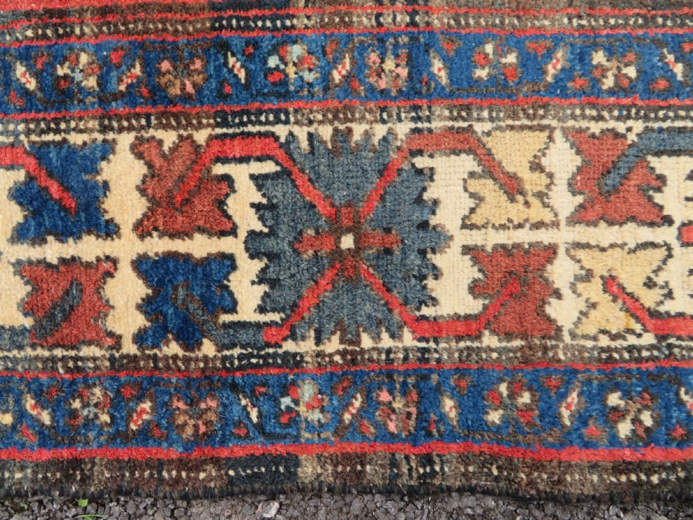 An antique Northwest Persian Zanjan Kelleh rug featuring a red field with diamond medallions surrounded by a wide cream, blue, and red Harshang crab border. View XI