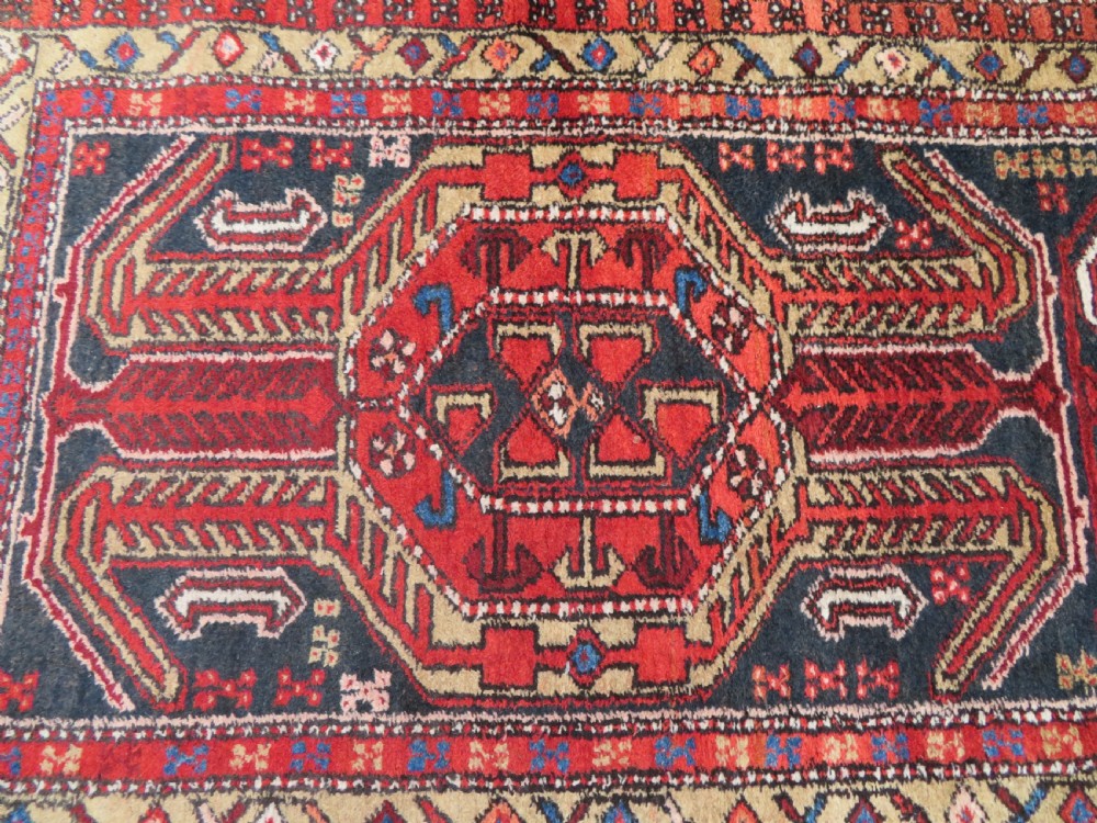 A long hand-knotted Persian Heriz runner rug featuring central geometric medallions in terracotta red and navy blue bordered by intricate geometric patterns. View III