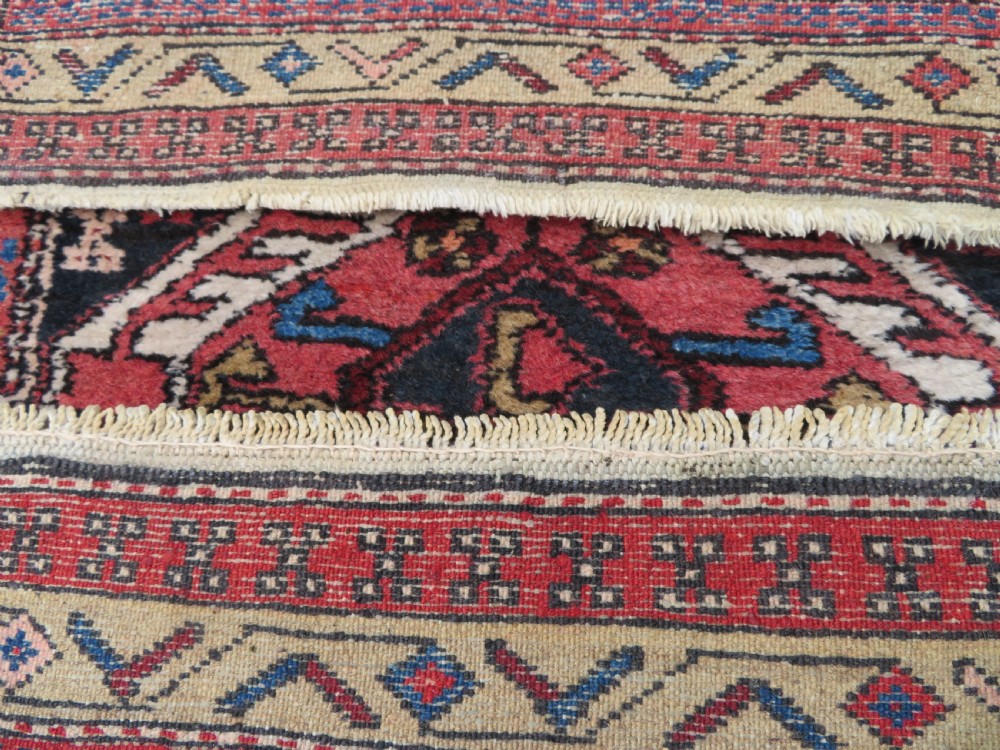 A long hand-knotted Persian Heriz runner rug featuring central geometric medallions in terracotta red and navy blue bordered by intricate geometric patterns. View XII