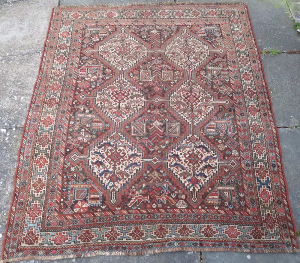 A rectangular hand-knotted antique Khamseh wool rug featuring geometric diamond medallions and intricate border patterns in terracotta, dark brown, and cream. View II