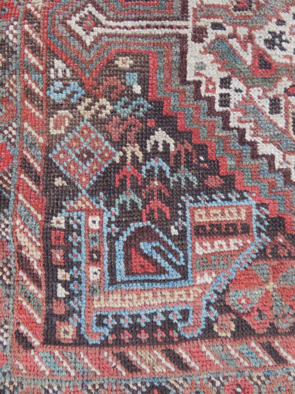 A rectangular hand-knotted antique Khamseh wool rug featuring geometric diamond medallions and intricate border patterns in terracotta, dark brown, and cream. View VII