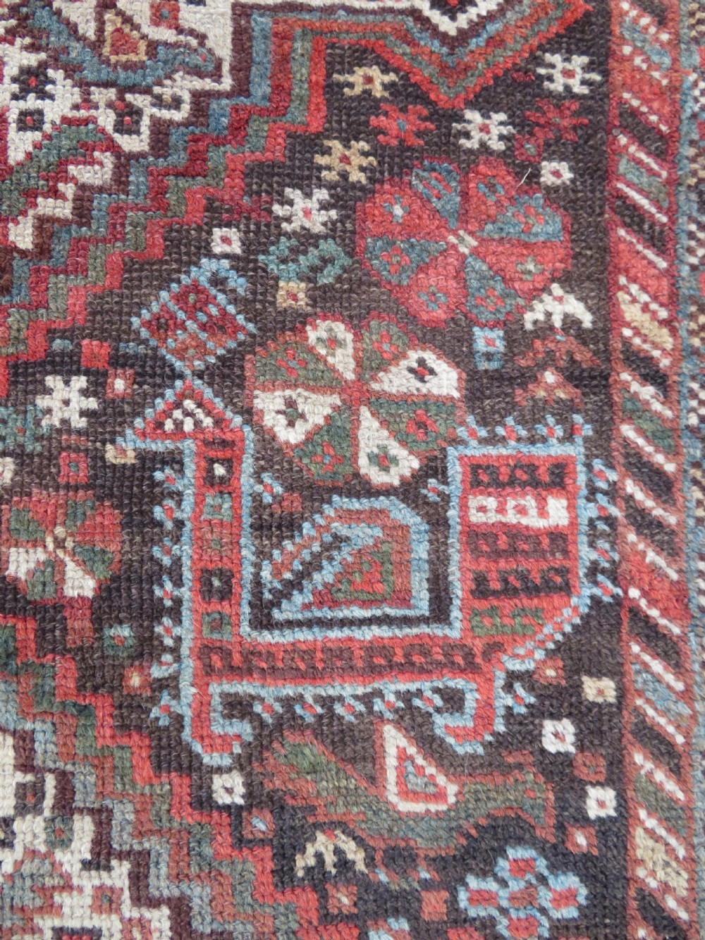 A rectangular hand-knotted antique Khamseh wool rug featuring geometric diamond medallions and intricate border patterns in terracotta, dark brown, and cream. View XII