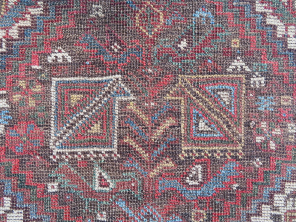 A rectangular hand-knotted antique Khamseh wool rug featuring geometric diamond medallions and intricate border patterns in terracotta, dark brown, and cream. View XVIII