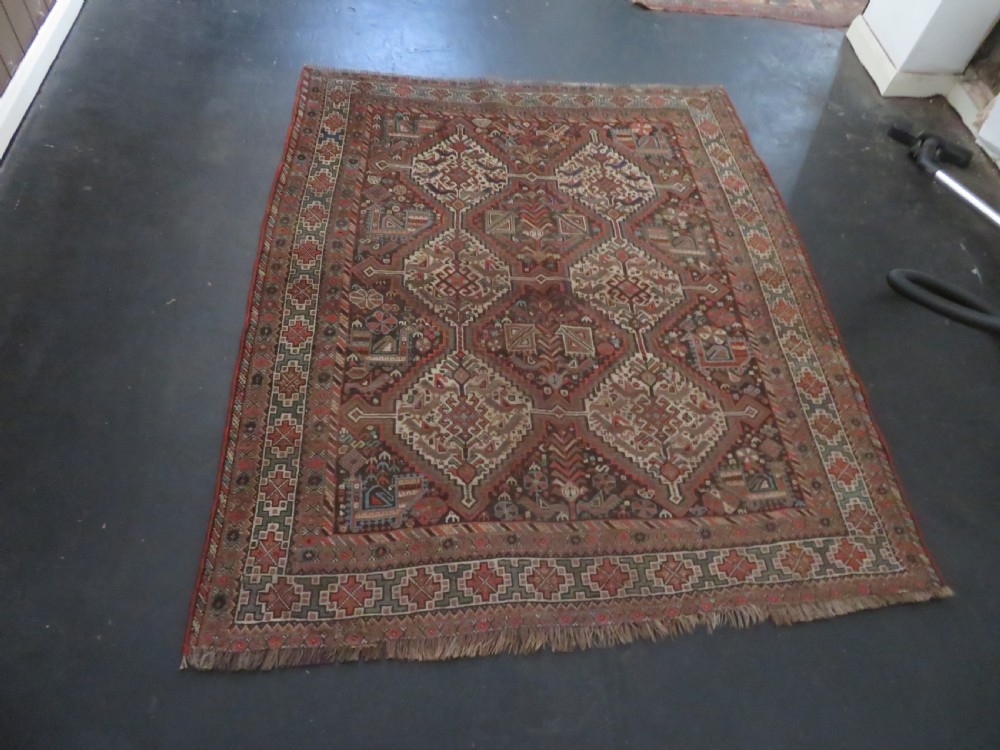 A rectangular hand-knotted antique Khamseh wool rug featuring geometric diamond medallions and intricate border patterns in terracotta, dark brown, and cream. View XXIX