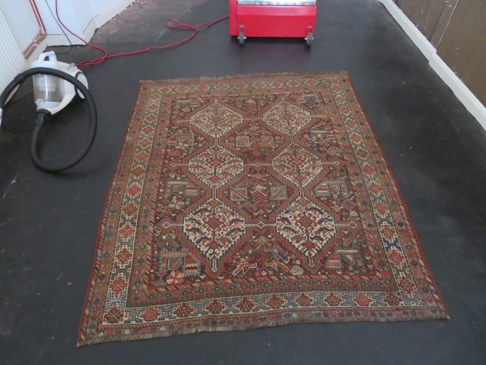A rectangular hand-knotted antique Khamseh wool rug featuring geometric diamond medallions and intricate border patterns in terracotta, dark brown, and cream. View XXX