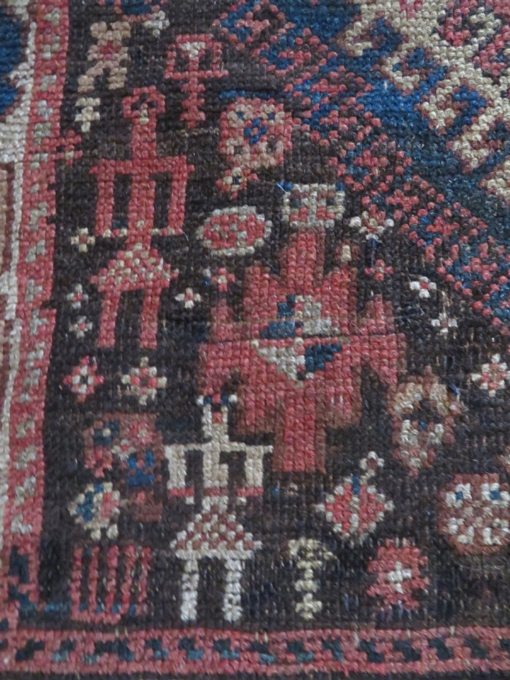 An antique hand-knotted wool runner rug featuring repeating geometric diamond medallions down a central dark field with multi-tiered tribal borders. View VI