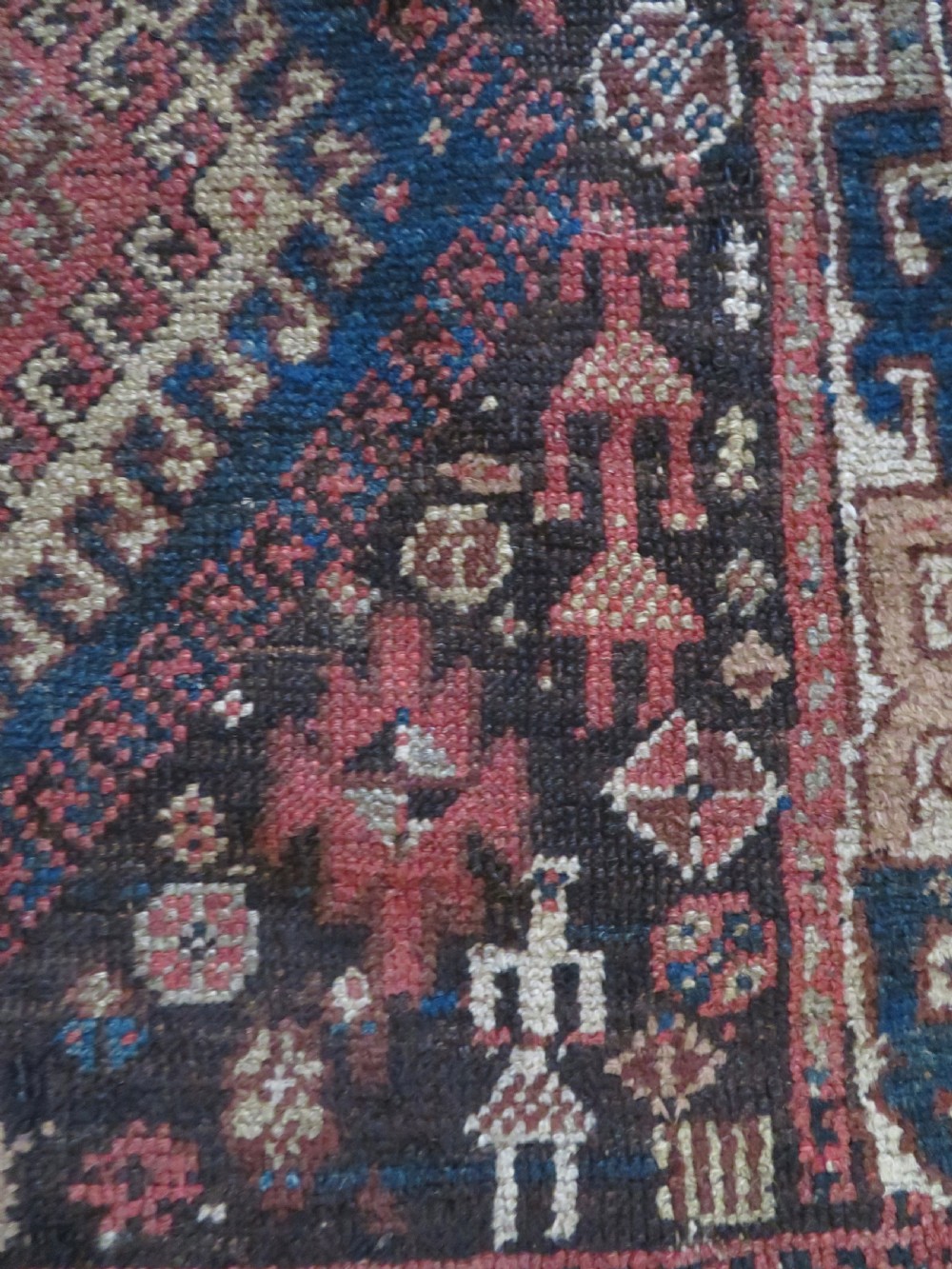 An antique hand-knotted wool runner rug featuring repeating geometric diamond medallions down a central dark field with multi-tiered tribal borders. View VII