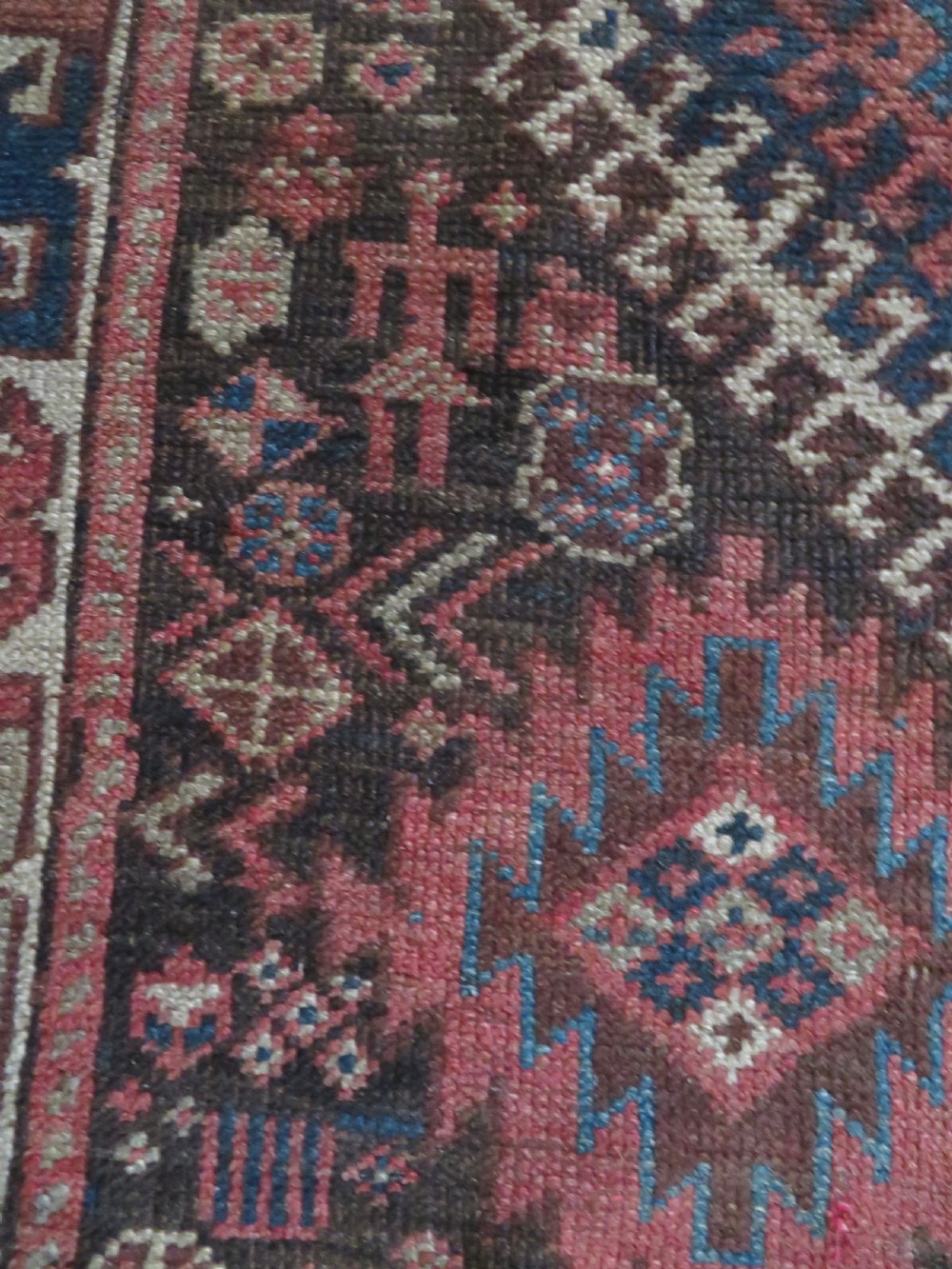 An antique hand-knotted wool runner rug featuring repeating geometric diamond medallions down a central dark field with multi-tiered tribal borders. View VIII