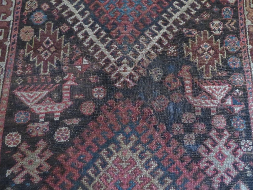 An antique hand-knotted wool runner rug featuring repeating geometric diamond medallions down a central dark field with multi-tiered tribal borders. View X