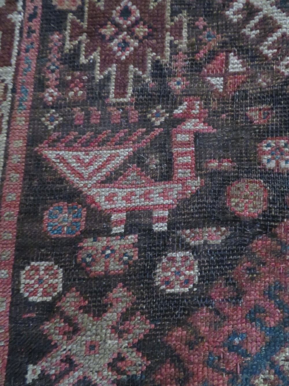 An antique hand-knotted wool runner rug featuring repeating geometric diamond medallions down a central dark field with multi-tiered tribal borders. View XI