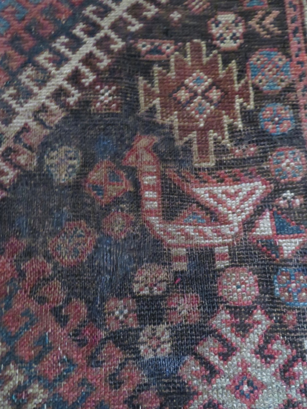 An antique hand-knotted wool runner rug featuring repeating geometric diamond medallions down a central dark field with multi-tiered tribal borders. View XII