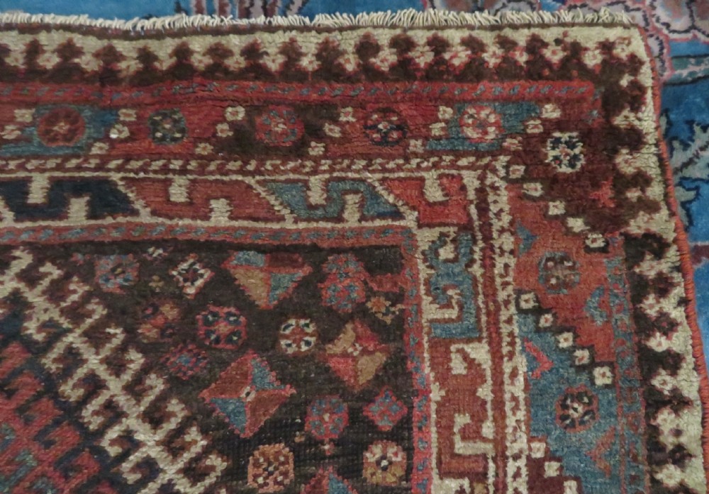 An antique hand-knotted wool runner rug featuring repeating geometric diamond medallions down a central dark field with multi-tiered tribal borders. View XIII