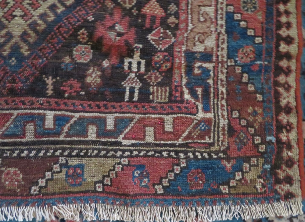 An antique hand-knotted wool runner rug featuring repeating geometric diamond medallions down a central dark field with multi-tiered tribal borders. View XV