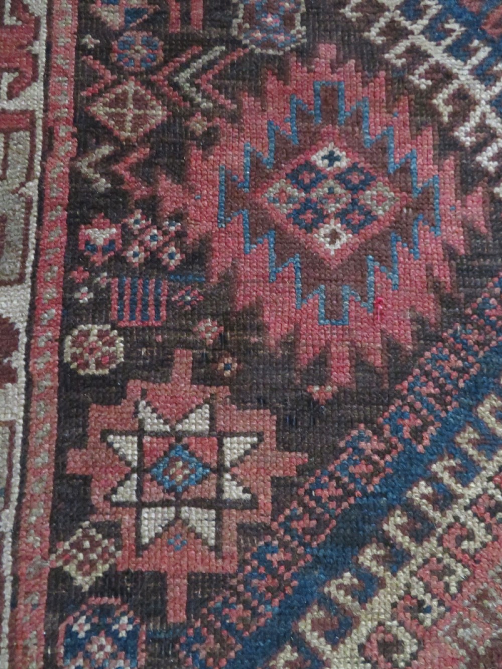 An antique hand-knotted wool runner rug featuring repeating geometric diamond medallions down a central dark field with multi-tiered tribal borders. View XVII