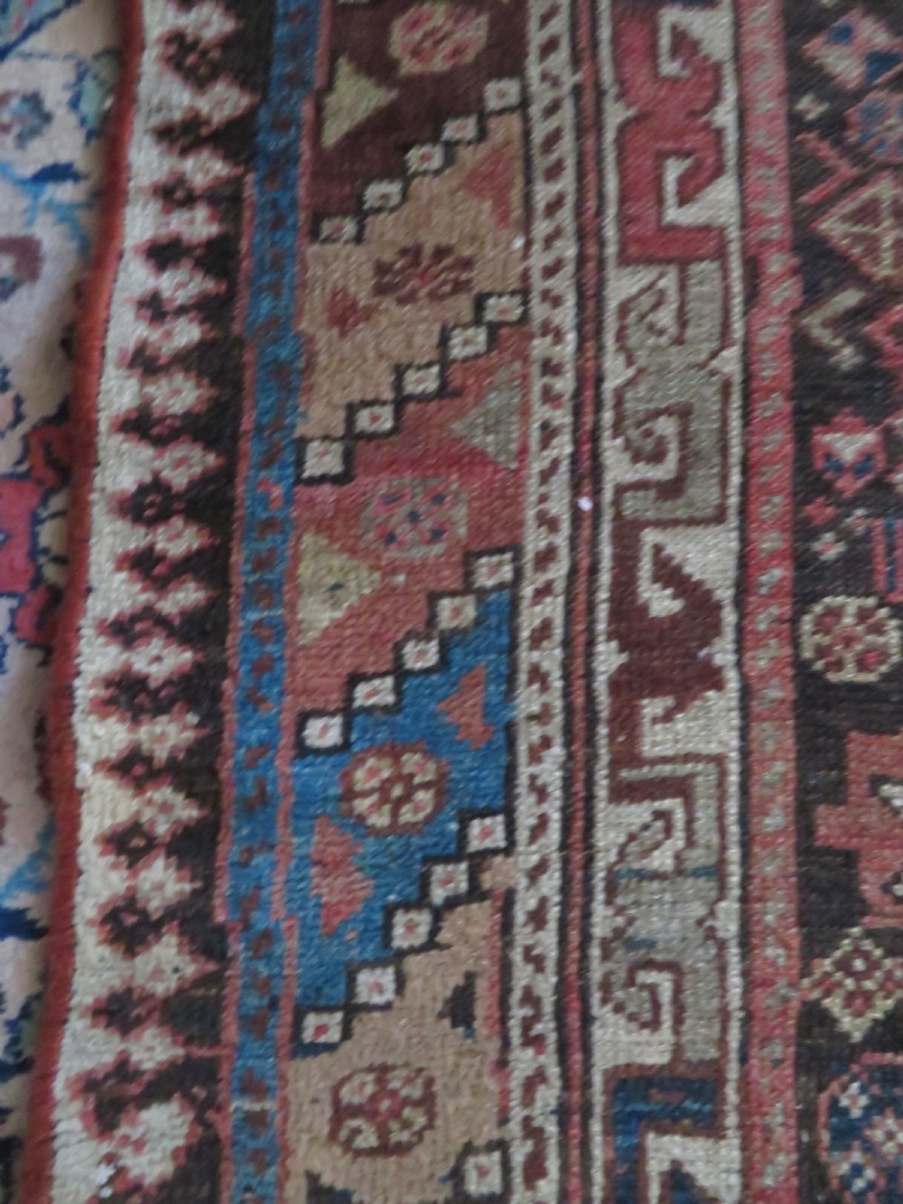 An antique hand-knotted wool runner rug featuring repeating geometric diamond medallions down a central dark field with multi-tiered tribal borders. View XVIII