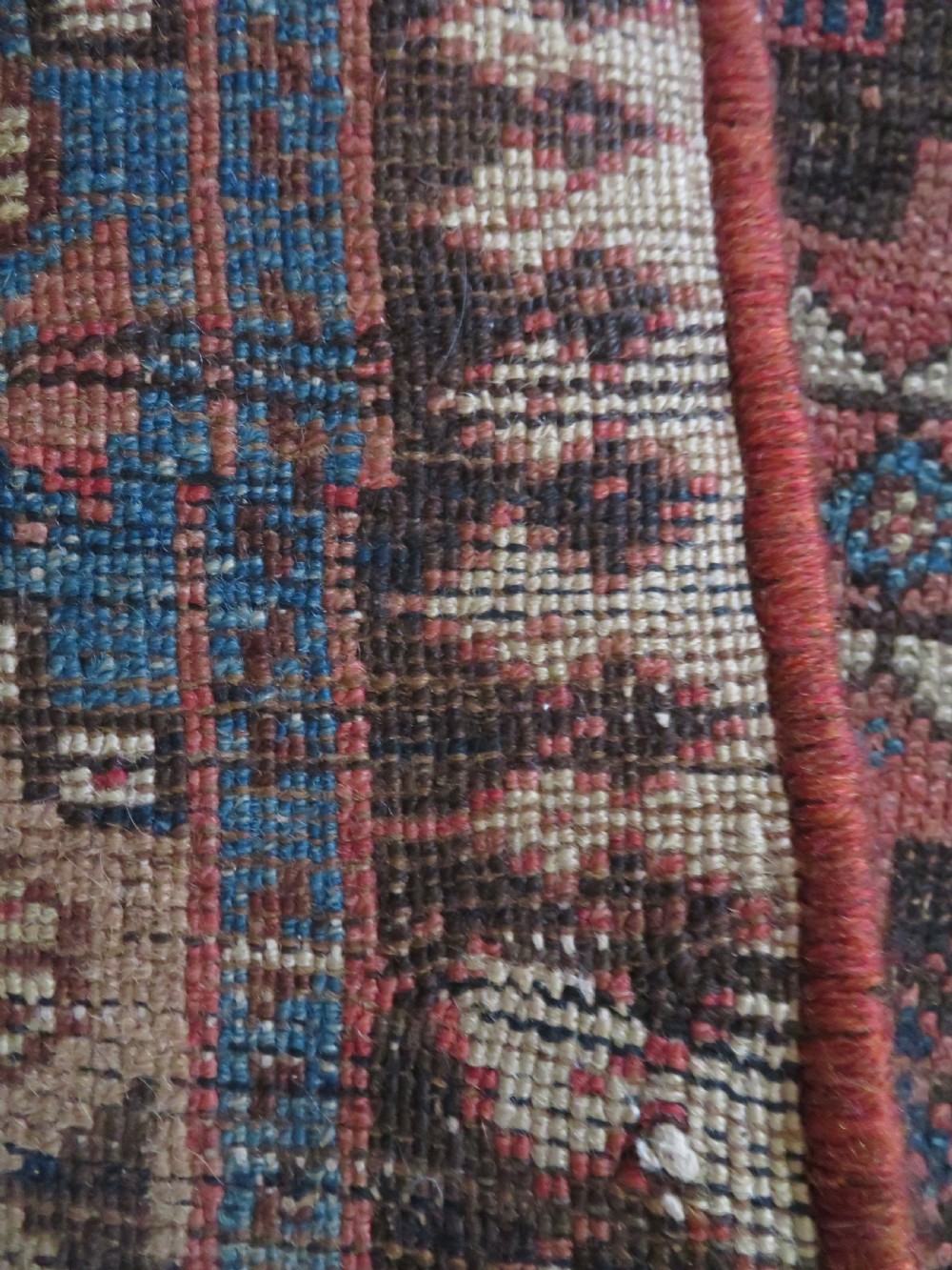 An antique hand-knotted wool runner rug featuring repeating geometric diamond medallions down a central dark field with multi-tiered tribal borders. View XIX