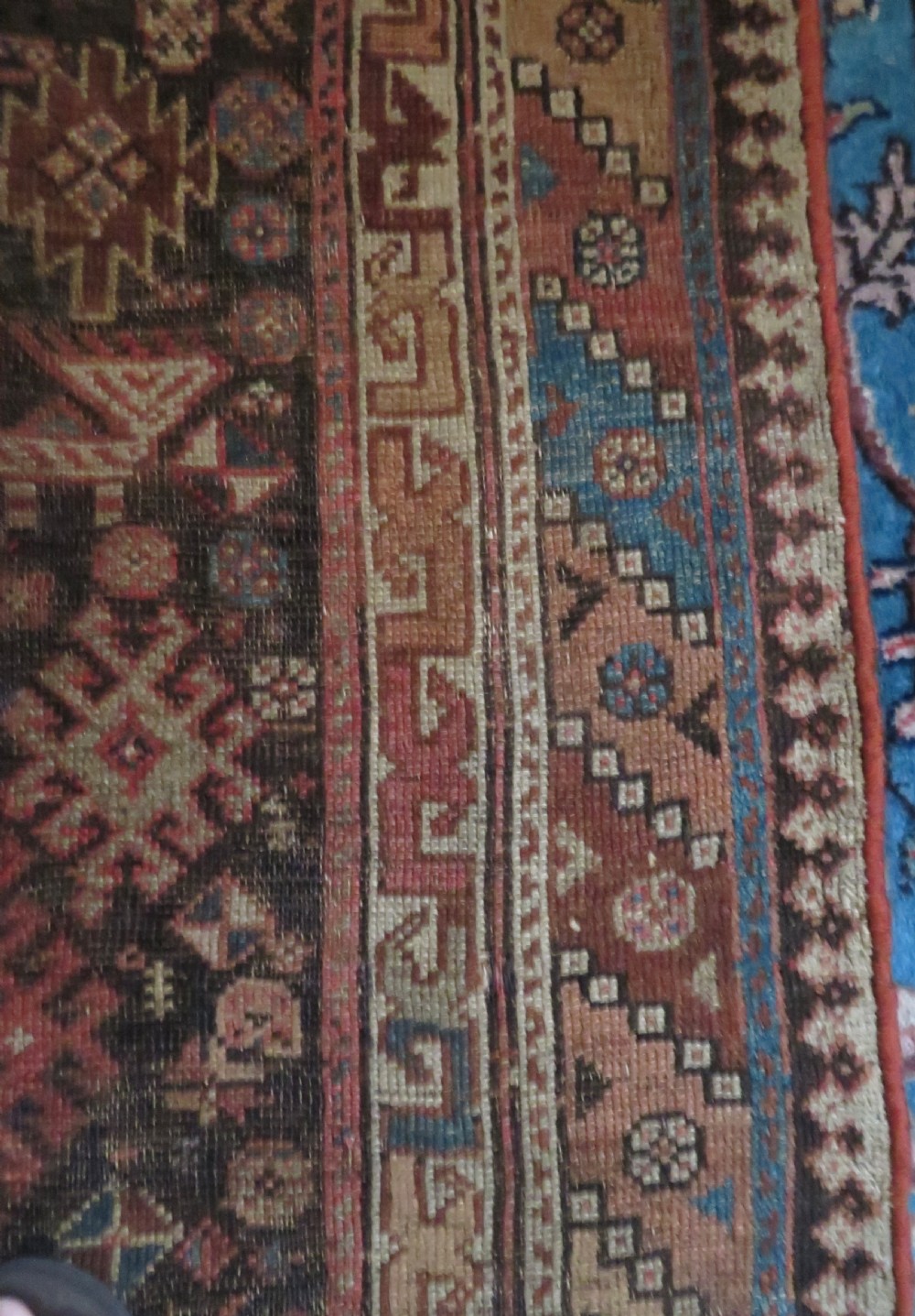 An antique hand-knotted wool runner rug featuring repeating geometric diamond medallions down a central dark field with multi-tiered tribal borders. View XX