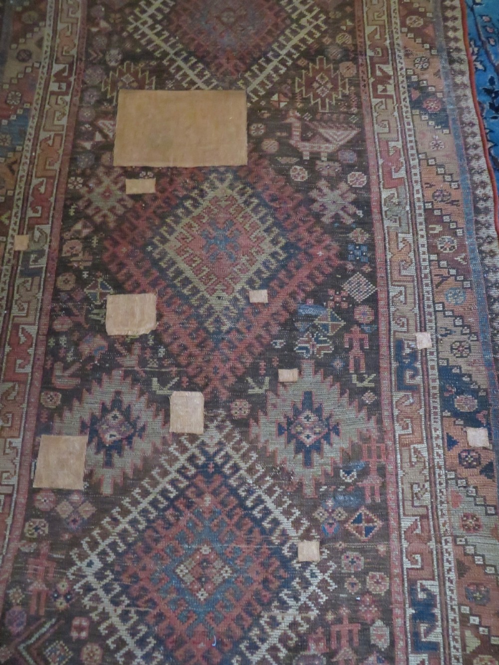 An antique hand-knotted wool runner rug featuring repeating geometric diamond medallions down a central dark field with multi-tiered tribal borders. View XXII