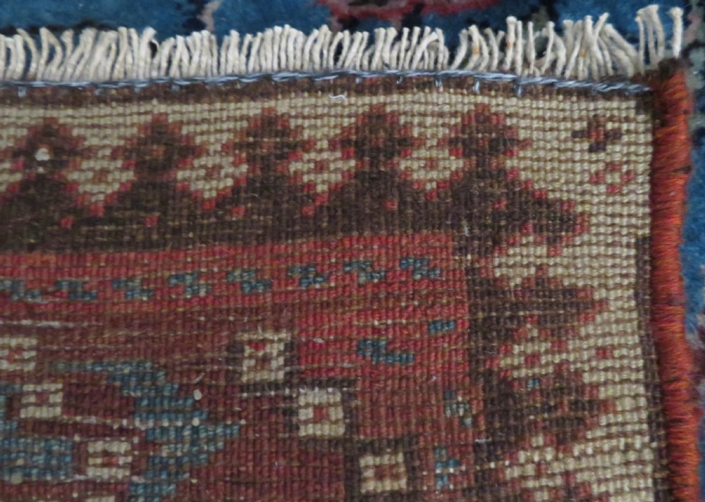 An antique hand-knotted wool runner rug featuring repeating geometric diamond medallions down a central dark field with multi-tiered tribal borders. View XXIV