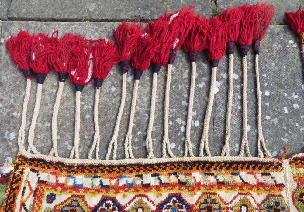 An antique cream handwoven wool Qashqai horse cover featuring colourful geometric patterns, human and camel motifs, and decorative edge tassels. View XIV