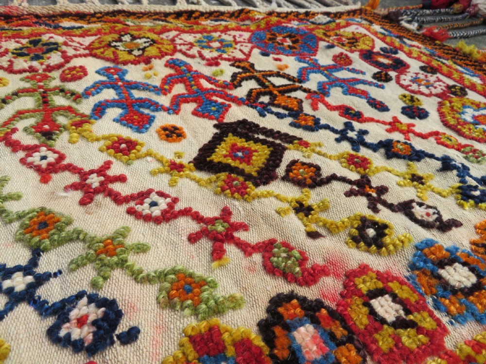 An antique cream handwoven wool Qashqai horse cover featuring colourful geometric patterns, human and camel motifs, and decorative edge tassels. View XV