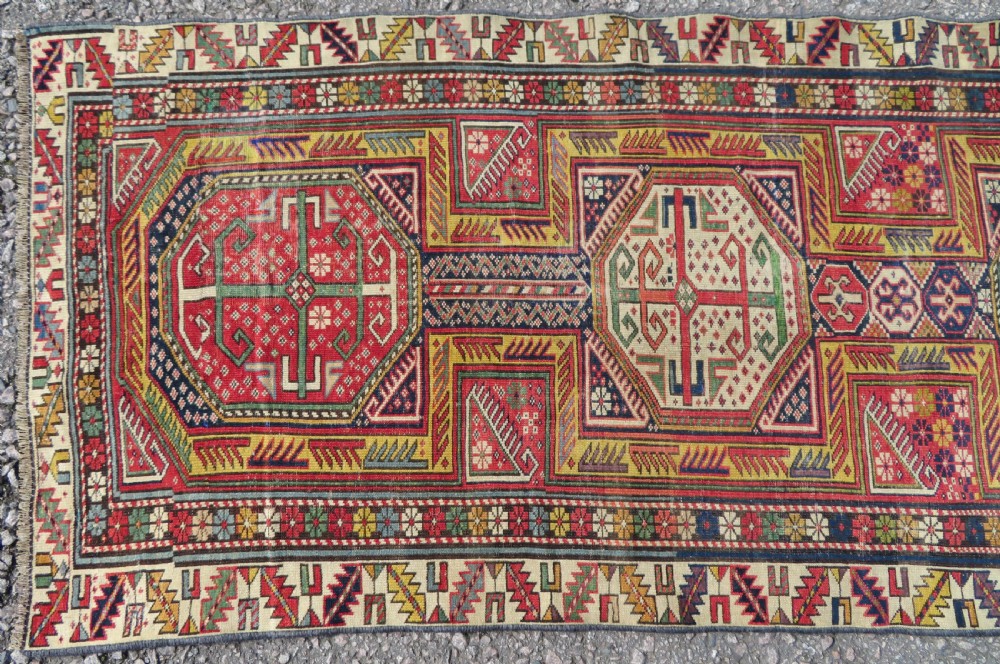 An antique Caucasian Shirvan wool runner rug with repeating geometric octagonal medallions framed by intricate multi-coloured borders. View V