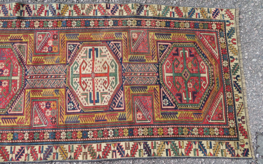 An antique Caucasian Shirvan wool runner rug with repeating geometric octagonal medallions framed by intricate multi-coloured borders. View VI