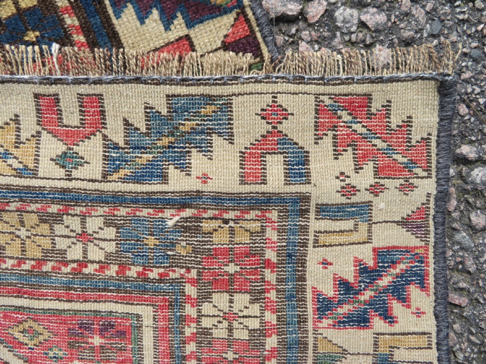 An antique Caucasian Shirvan wool runner rug with repeating geometric octagonal medallions framed by intricate multi-coloured borders. View X