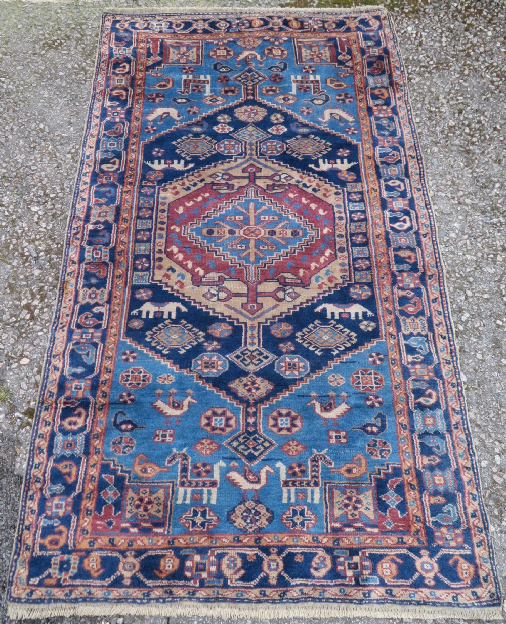 An antique blue-ground hand-knotted Turkish Kurdish tribal wool rug featuring a central geometric medallion and stylized animal motifs.