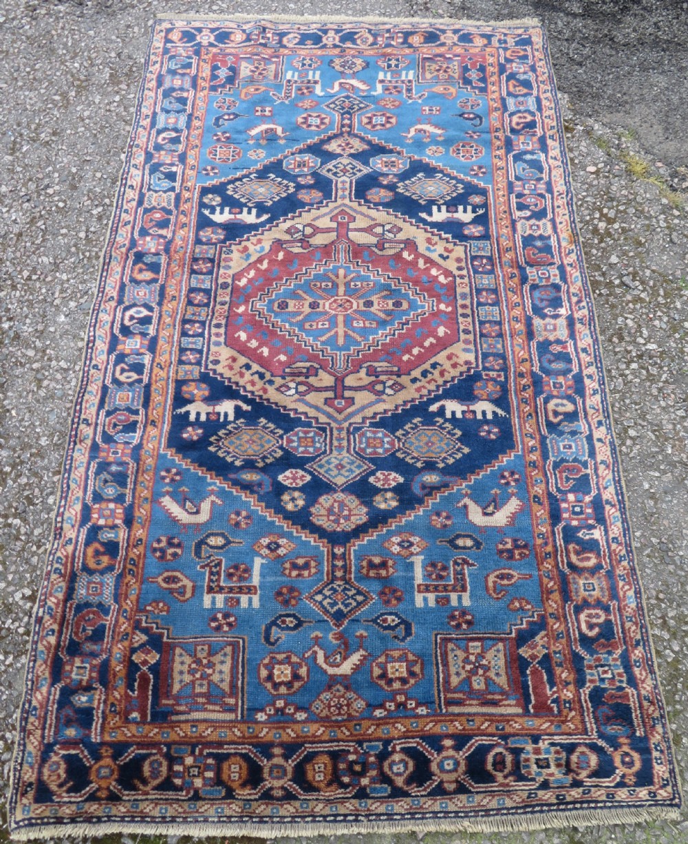 An antique blue-ground hand-knotted Turkish Kurdish tribal wool rug featuring a central geometric medallion and stylized animal motifs. View II