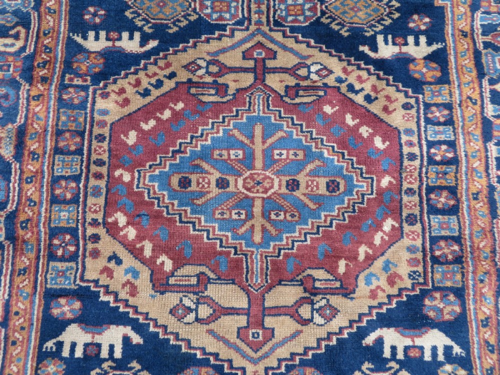 An antique blue-ground hand-knotted Turkish Kurdish tribal wool rug featuring a central geometric medallion and stylized animal motifs. View III