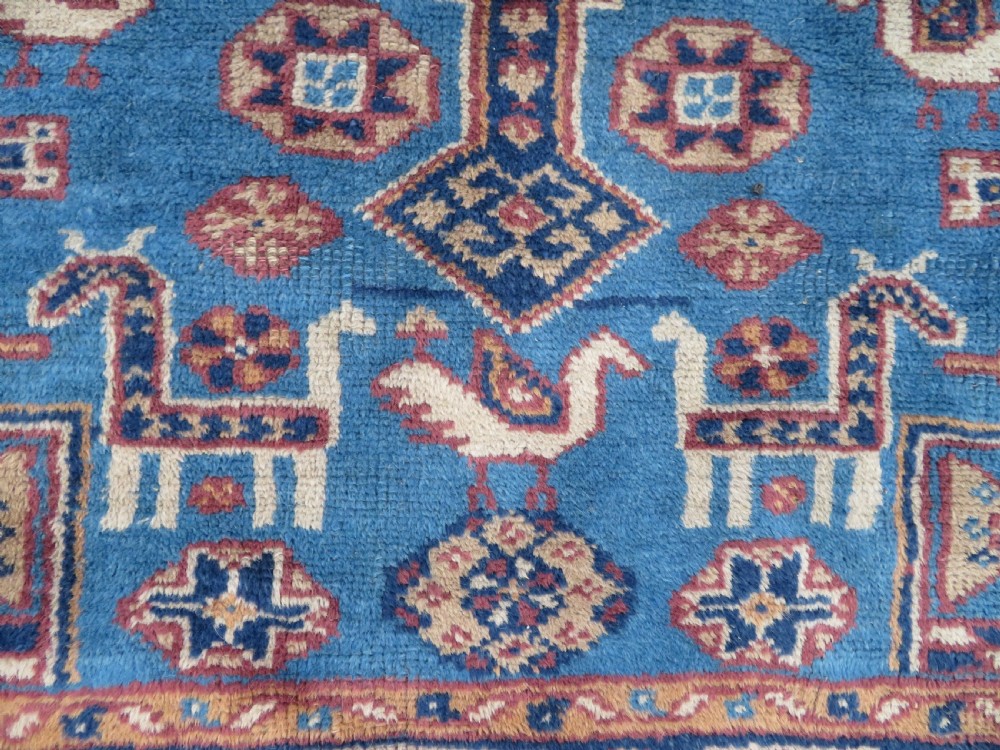 An antique blue-ground hand-knotted Turkish Kurdish tribal wool rug featuring a central geometric medallion and stylized animal motifs. View IV