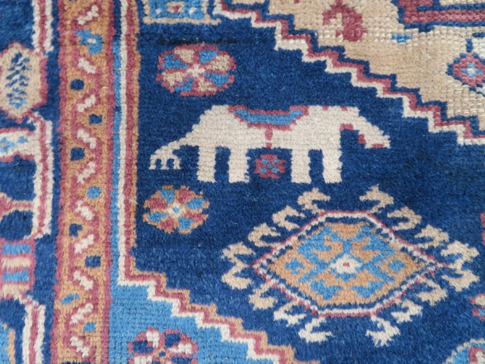 An antique blue-ground hand-knotted Turkish Kurdish tribal wool rug featuring a central geometric medallion and stylized animal motifs. View VI
