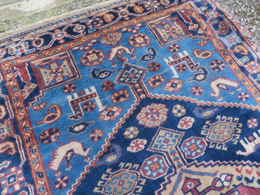 An antique blue-ground hand-knotted Turkish Kurdish tribal wool rug featuring a central geometric medallion and stylized animal motifs. View VII